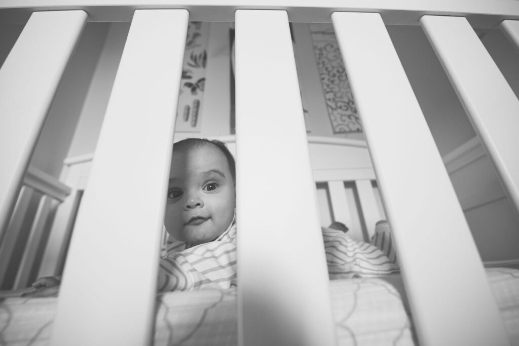 a newborn baby poses indoors inside its crib for its newborn lifestyle family session