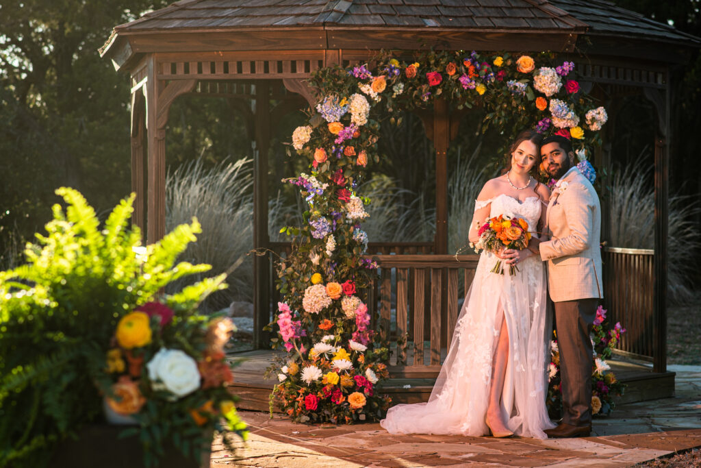 Couple in front of decorated gazebo during sunset.