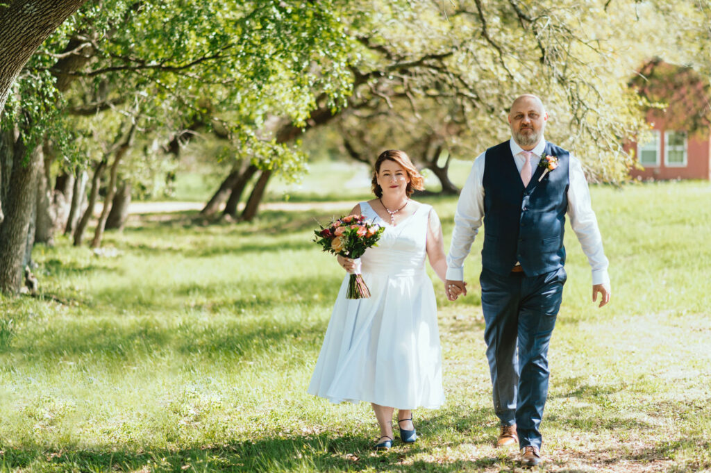 a newly-married couple walks along a grove at Duchman Winery