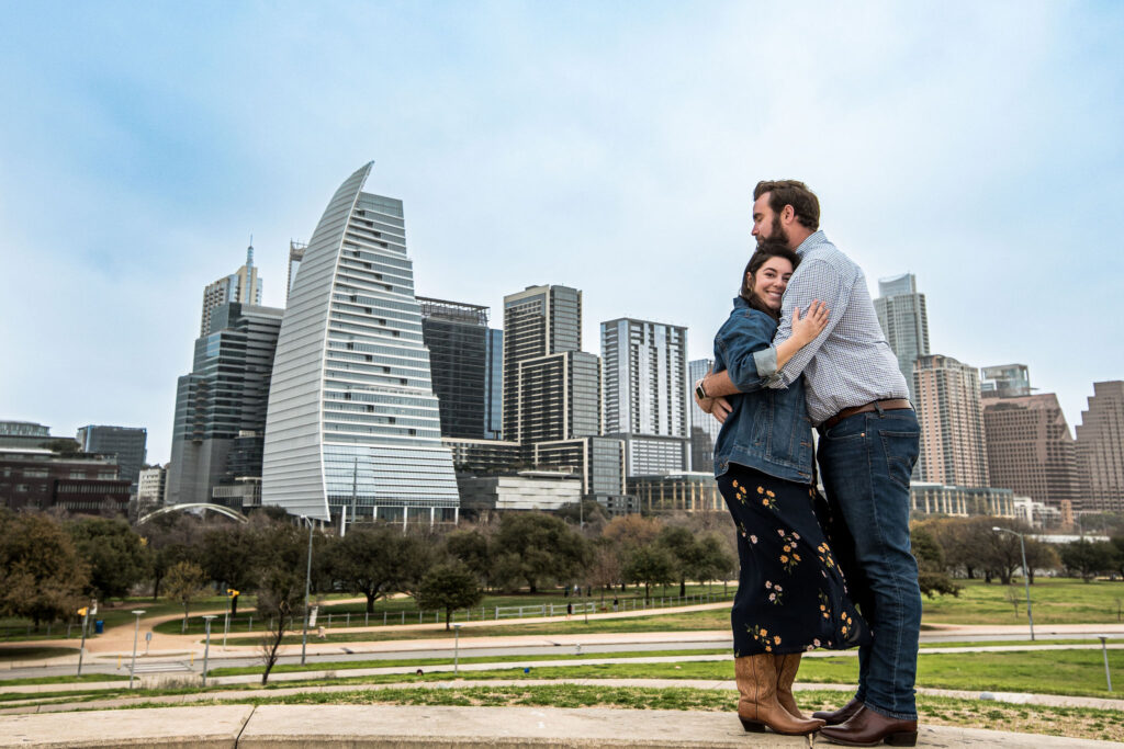 A couple holds eachother in front of downtown Austin for their proposal photos