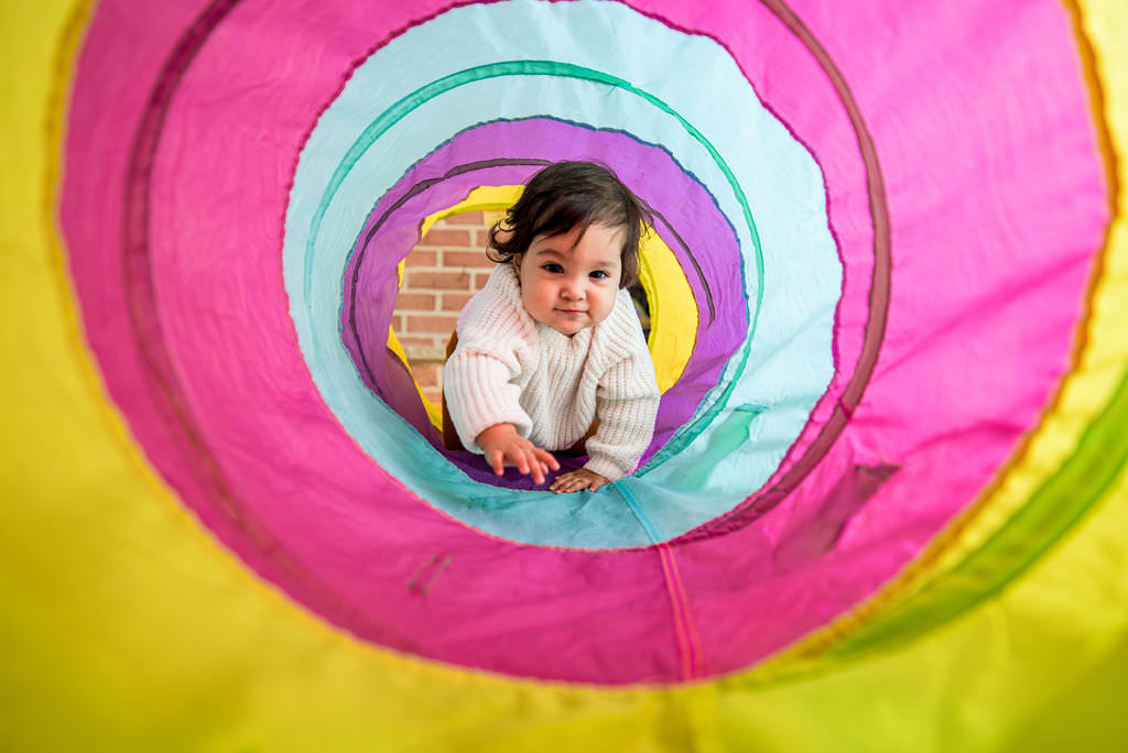 a toddler crawls through a chute at home for their family session