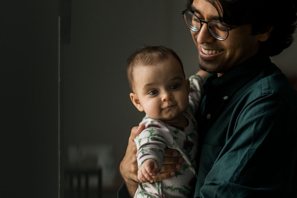 a father holds his newborn baby at their indoor family photography session