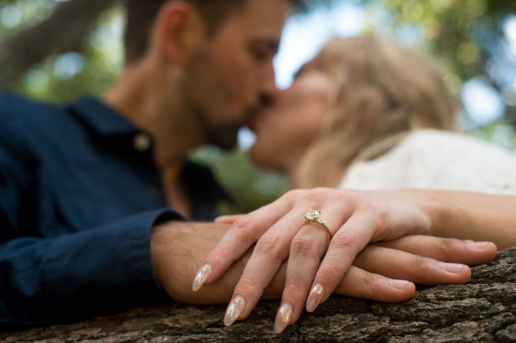 an engaged woman kissing her fiance with the engagement ring in the forefront