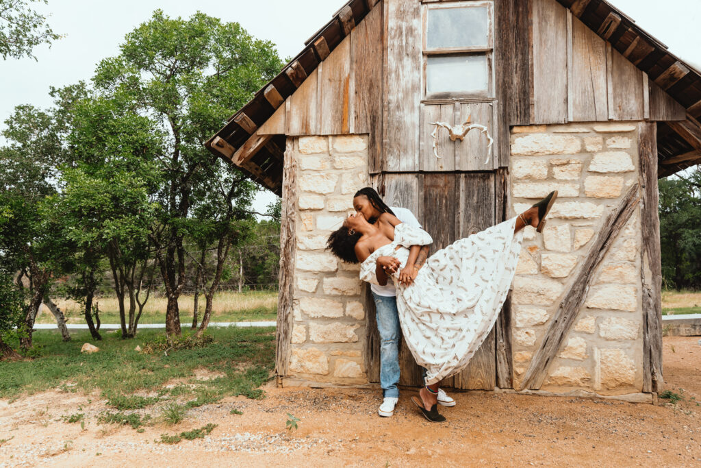 a LGBTQ couple dancing in front of a stone cabin